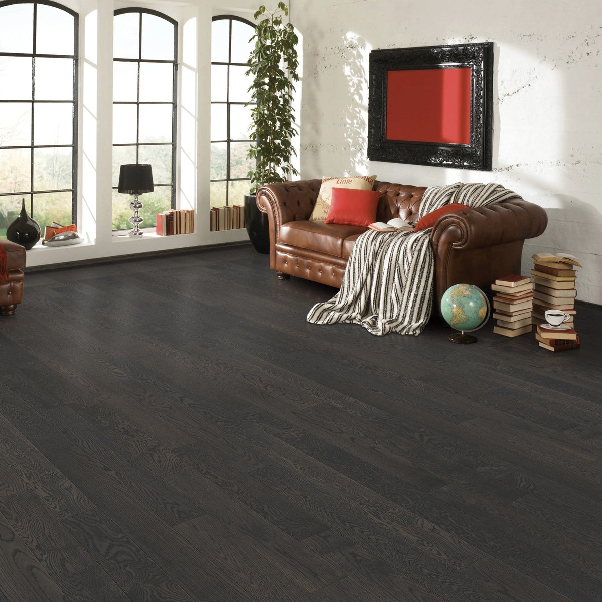 Living room with dark oak hardwood flooring, brown leather sofa, and large windows.