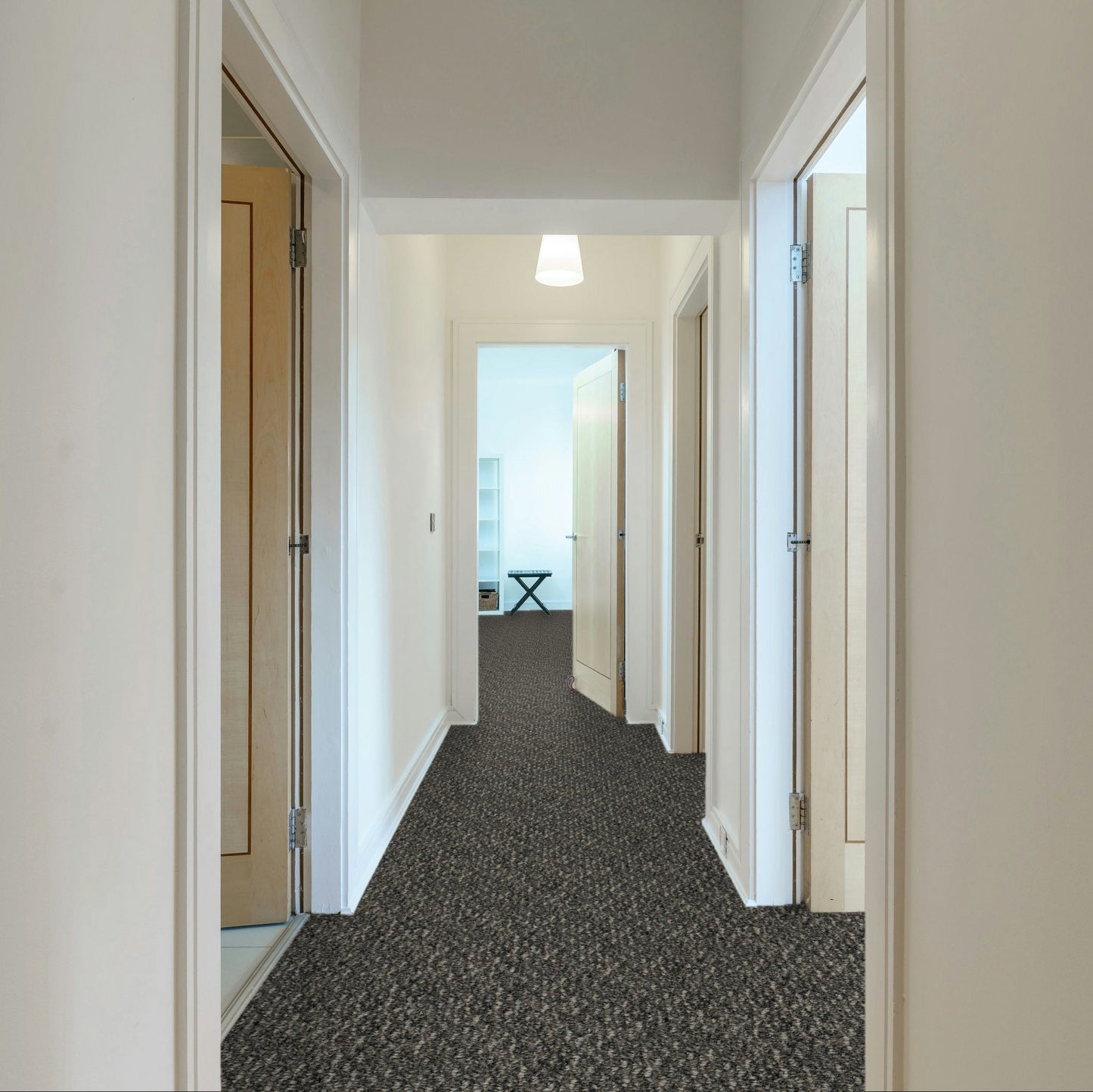 Long hallway with carpeted floor and white walls, leading to a room with a desk and window. Beaulieu carpet Nostalgia Mountain Rocks made in Canada.
