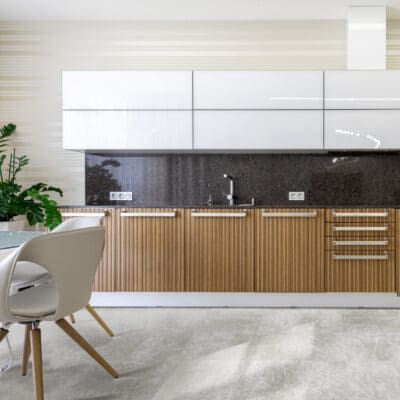 Modern kitchen with wooden and white cabinets, black backsplash, and stainless steel appliances. Featuring Coastline - Sorrento luxury vinyl tile