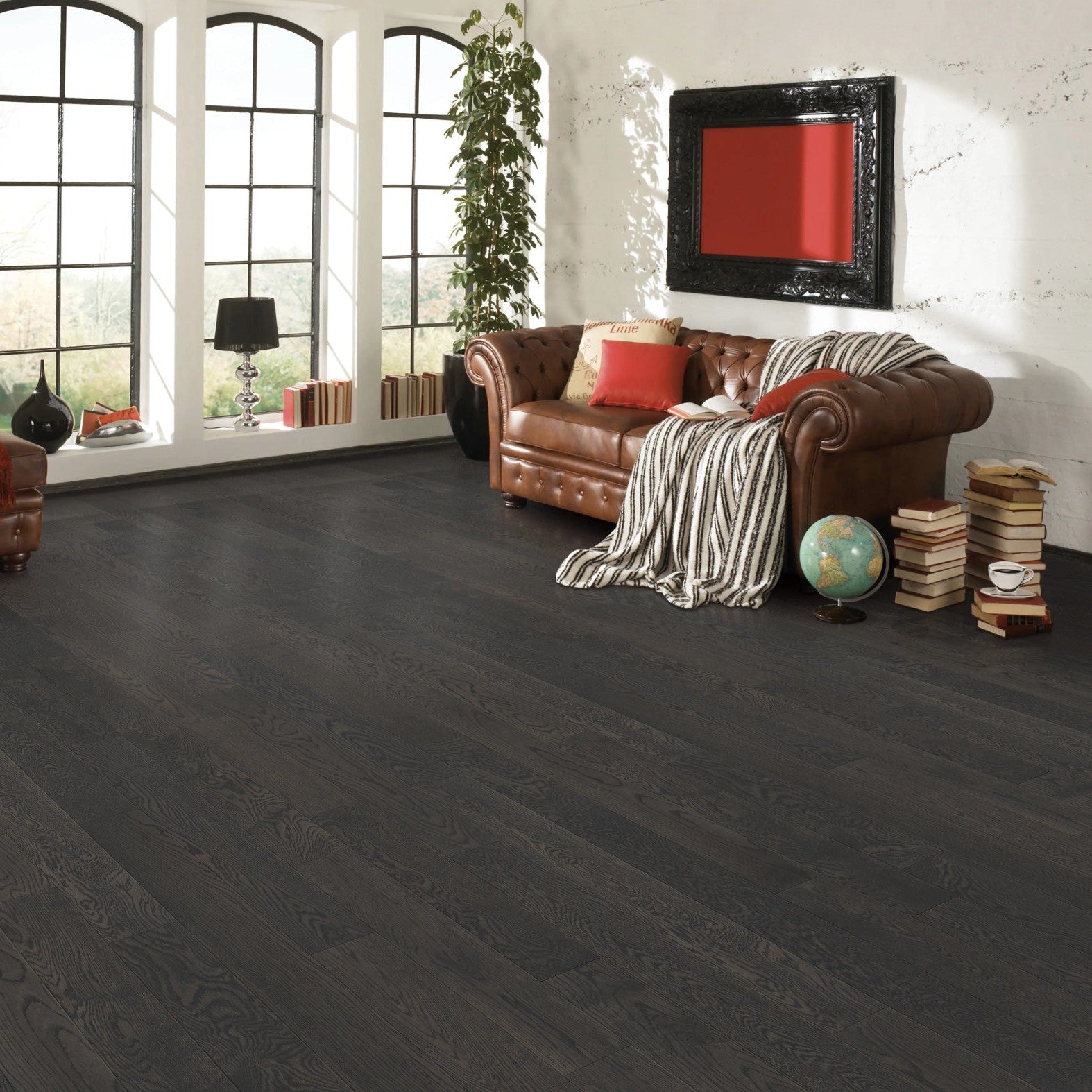 Living room with dark oak hardwood flooring, brown leather sofa, and large windows.