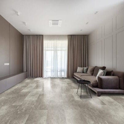 Modern living room with a sofa, bookshelves, and large windows. Coastline - Ravello luxury vinyl floor tile