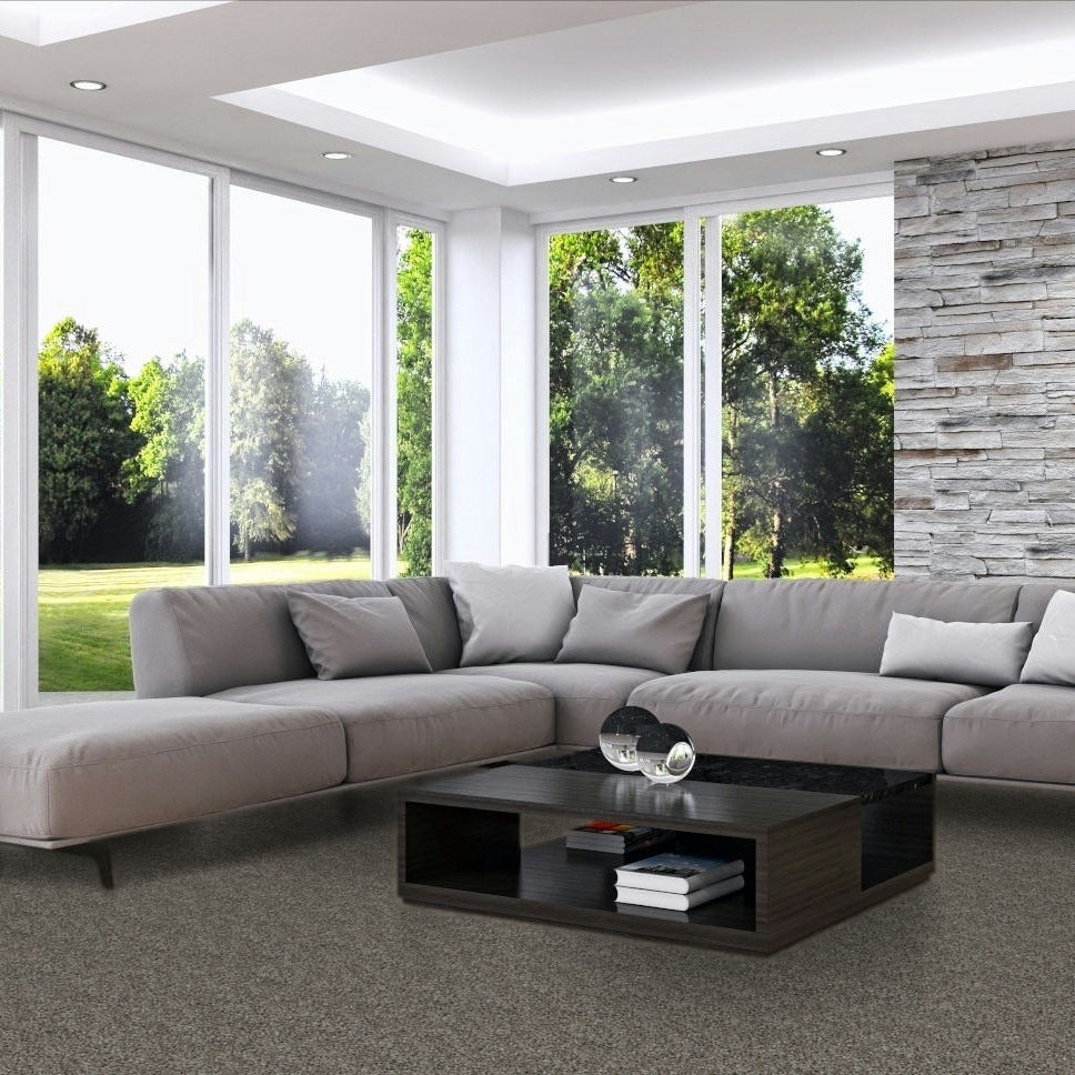 Modern living room with a gray sectional sofa, coffee table, and large windows. Romantic Getaway Putty Grey carpet made in Canada.